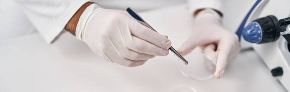 Young hispanic man scientist holding sample with tweezer at laboratory